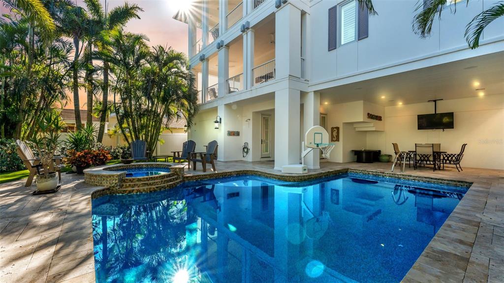 A swimming pool and hot tub sit on a patio beneath a multi-story white house — 1013 ELDORADO AVENUE, CLEARWATER, FL