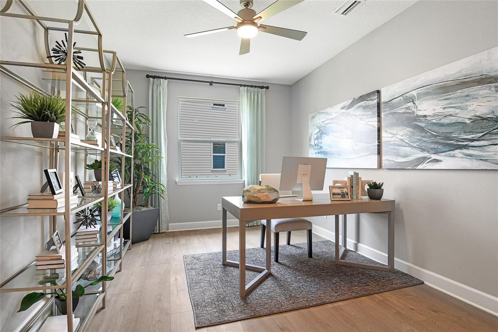 A home office features a desk, a tall metal shelving unit, and two large wall paintings — 55 PONCE PRESERVE DRIVE, PALM COAST, FL