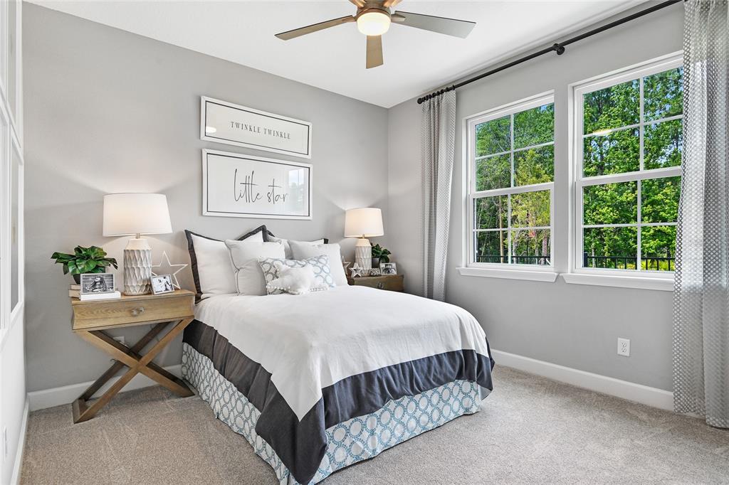 A bedroom features a bed with a patterned bed skirt, two nightstands, and two windows — 55 PONCE PRESERVE DRIVE, PALM COAST, FL