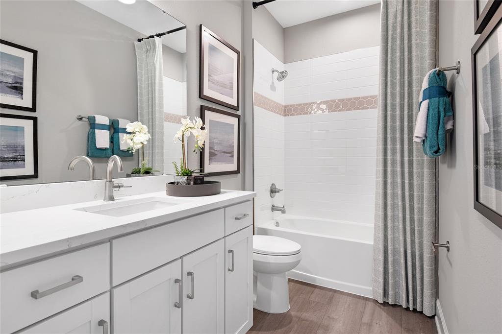 A modern bathroom features a white vanity, a tub-shower combination, and wood-look flooring — 55 PONCE PRESERVE DRIVE, PALM COAST, FL