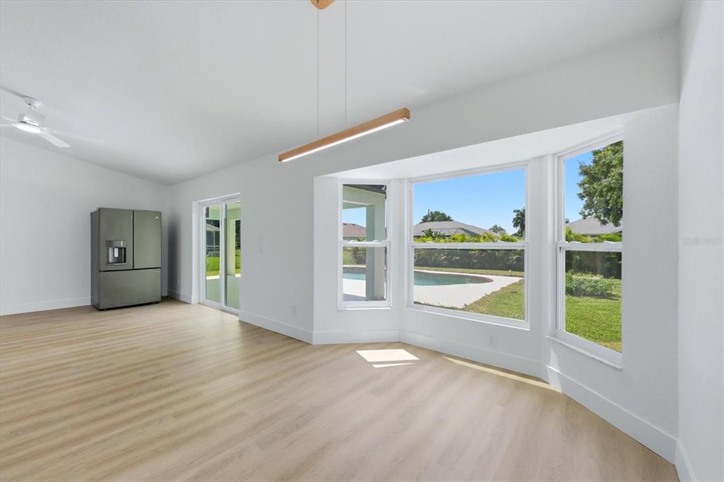 A modern kitchen with white cabinets and stainless steel appliances opens to a dining area — 27215 PUNTA CABELLO COURT, PUNTA GORDA, FL