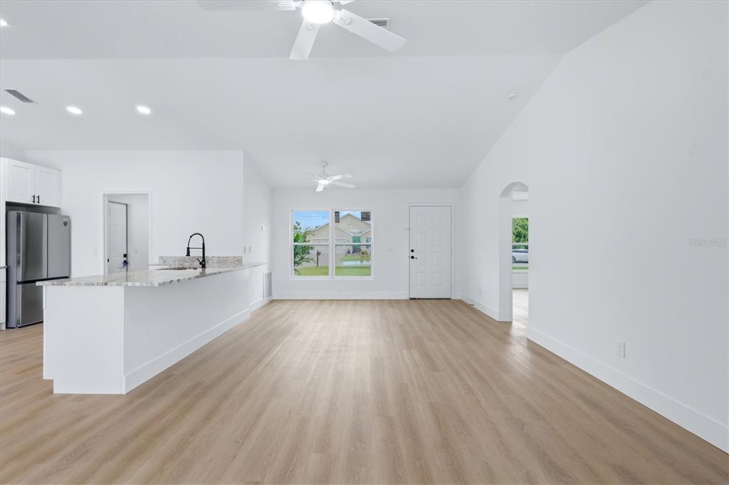 An empty room with light wood flooring, a bay window, and a stainless steel refrigerator — 27215 PUNTA CABELLO COURT, PUNTA GORDA, FL
