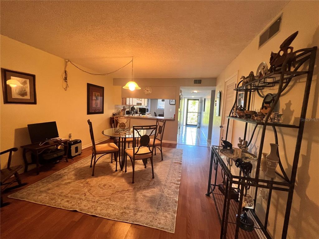A dining area with a glass table, chairs, and a metal shelving unit on wood floors — 9433 HARBOR GREENS WAY UNIT 404, SEMINOLE, FL