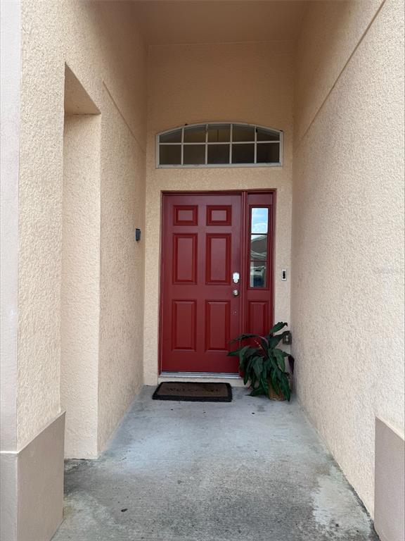 A red front door with a side window and arched transom sits in a recessed entryway — 742 OLD BRIDGE CIRCLE, DAVENPORT, FL