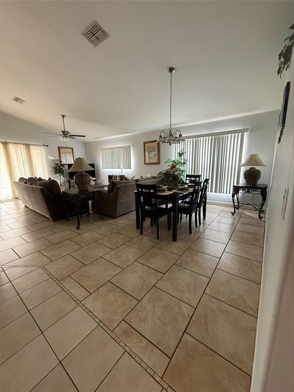 An open-concept living and dining area features tile flooring, neutral walls, and a vaulted ceiling — 742 OLD BRIDGE CIRCLE, DAVENPORT, FL
