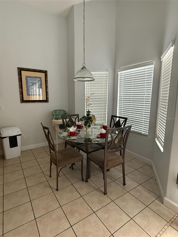 A dining area features a glass-topped table, four chairs, and a pendant light — 742 OLD BRIDGE CIRCLE, DAVENPORT, FL
