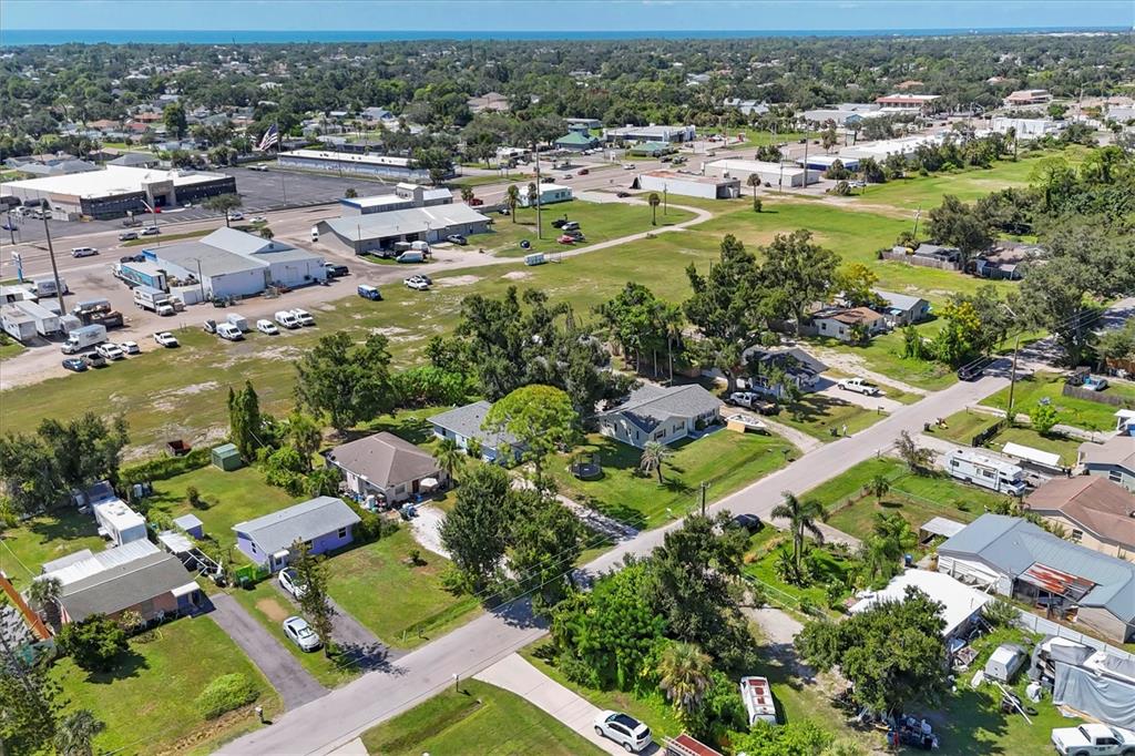 An aerial view shows a residential neighborhood with houses, large grassy lots, and nearby commercial buildings — 2214 PARK ROAD, VENICE, FL