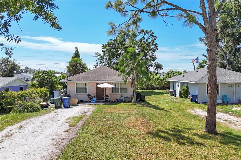 A single-story house with a tan exterior sits between two other homes on a grassy lot — 2214 PARK ROAD, VENICE, FL