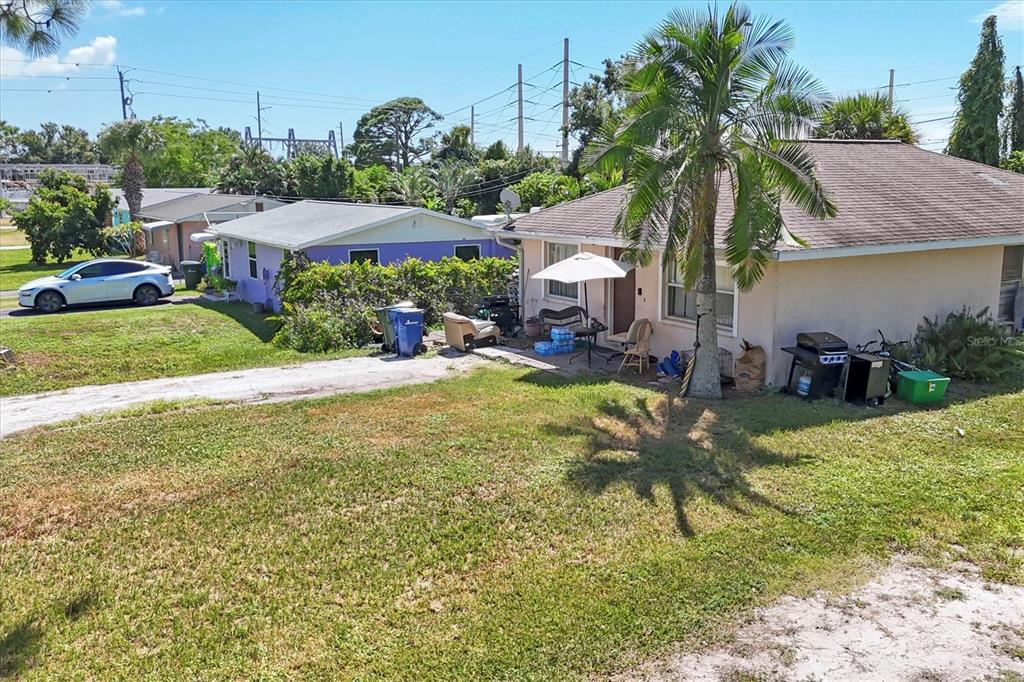 An exterior view of a tan house with a palm tree and a neighboring purple house — 2214 PARK ROAD, VENICE, FL