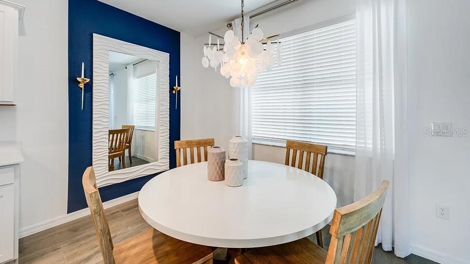 A dining room features a round white table, wooden chairs, and a large decorative mirror — 3613 AMBERSWEET CROSSING, PARRISH, FL