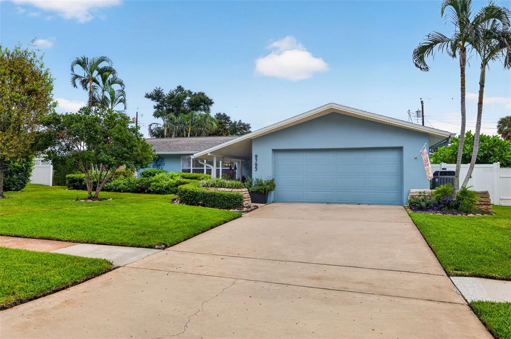A light blue single-story house with a two-car garage and a concrete driveway — 9795 PORTSIDE DRIVE, SEMINOLE, FL