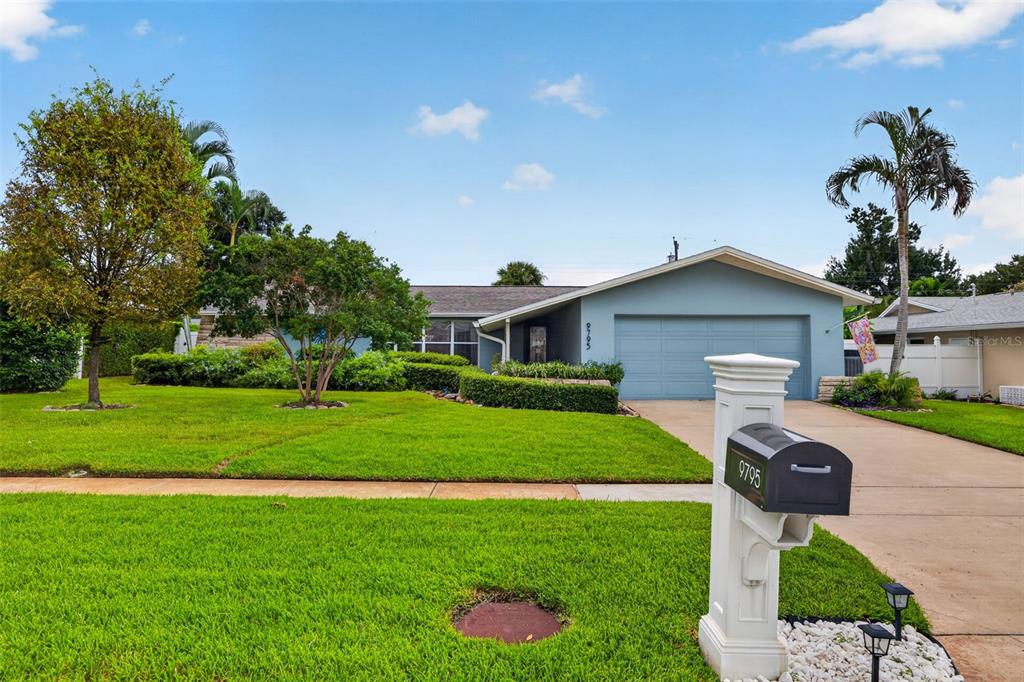 A single-story house with a blue exterior, a two-car garage, and a manicured lawn — 9795 PORTSIDE DRIVE, SEMINOLE, FL
