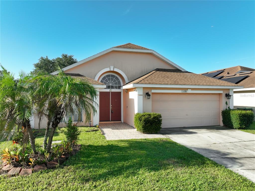 A single-story house with a tan stucco exterior, a two-car garage, and a palm tree — 11781 HATCHER CIRCLE, ORLANDO, FL