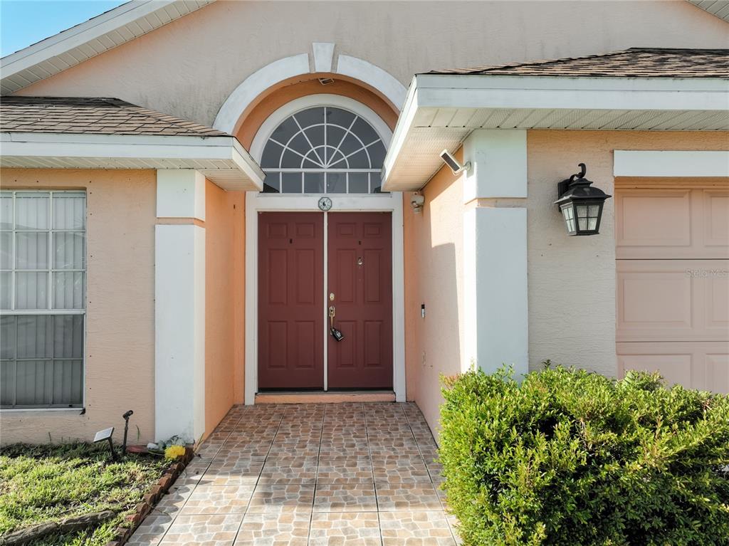The exterior view shows a peach-colored house with a tiled entryway and double front doors — 11781 HATCHER CIRCLE, ORLANDO, FL