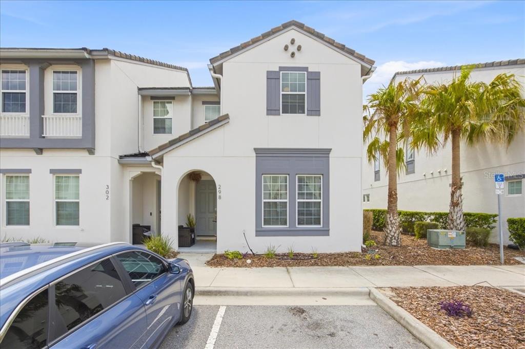 A two-story townhouse exterior with white stucco walls, grey trim, and a covered front entrance — 298 CAPTIVA DRIVE, DAVENPORT, FL