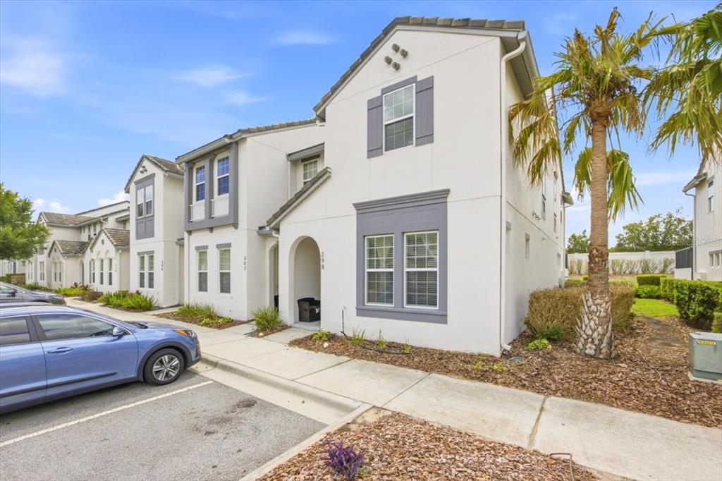 A two-story townhouse with white stucco walls, gray trim, and a palm tree out front — 298 CAPTIVA DRIVE, DAVENPORT, FL