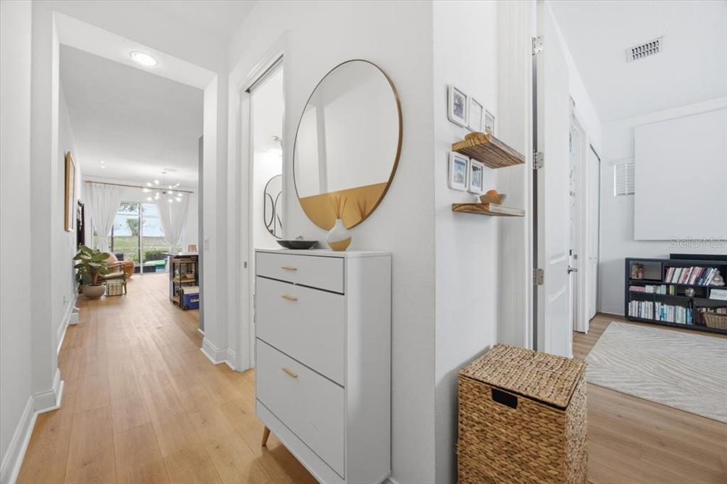 A hallway with light wood floors leads to a living area past a white cabinet — 298 CAPTIVA DRIVE, DAVENPORT, FL