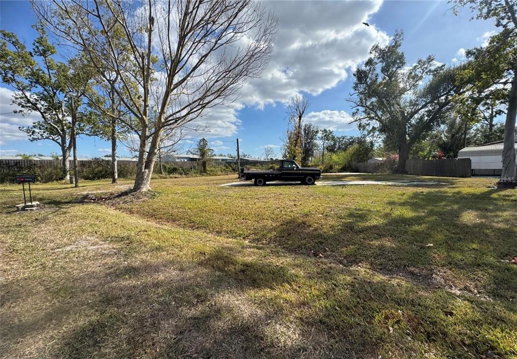 A black flatbed truck is parked on a grassy lot with scattered trees — 11854 SW LOOP TERRACE, ARCADIA, FL