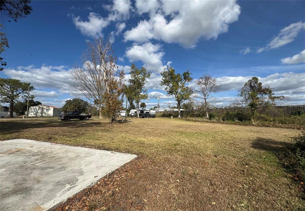A large, grassy lot features a concrete pad, a parked truck, and a travel trailer — 11854 SW LOOP TERRACE, ARCADIA, FL