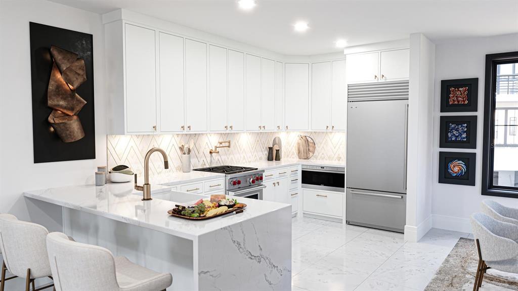 A modern kitchen features white cabinetry, marble countertops, a stainless steel refrigerator, and gold fixtures — 2360 OCEAN SHORE BOULEVARD UNIT 202, ORMOND BEACH, FL