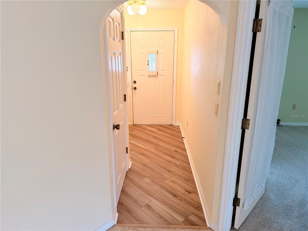 A spacious, carpeted living area features light yellow walls, ceiling fans, and multiple windows — 1241 SHAMROCK DRIVE, SEBRING, FL