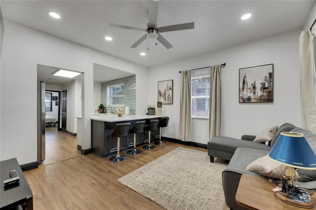 A living room with a kitchen breakfast bar, gray sectional sofa, and wood-look flooring — 1009 E COLUMBUS DRIVE, TAMPA, FL