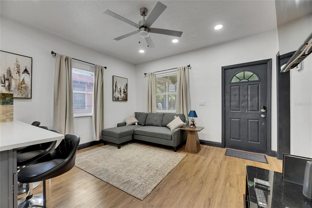 A living room with a gray sectional sofa, a ceiling fan, and a front door — 1009 E COLUMBUS DRIVE, TAMPA, FL