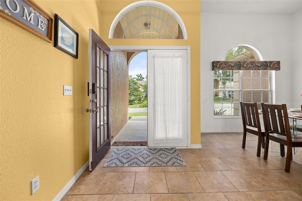 An entryway with tile flooring, yellow walls, and an open front door leading outside — 327 GREELEY LOOP, DAVENPORT, FL