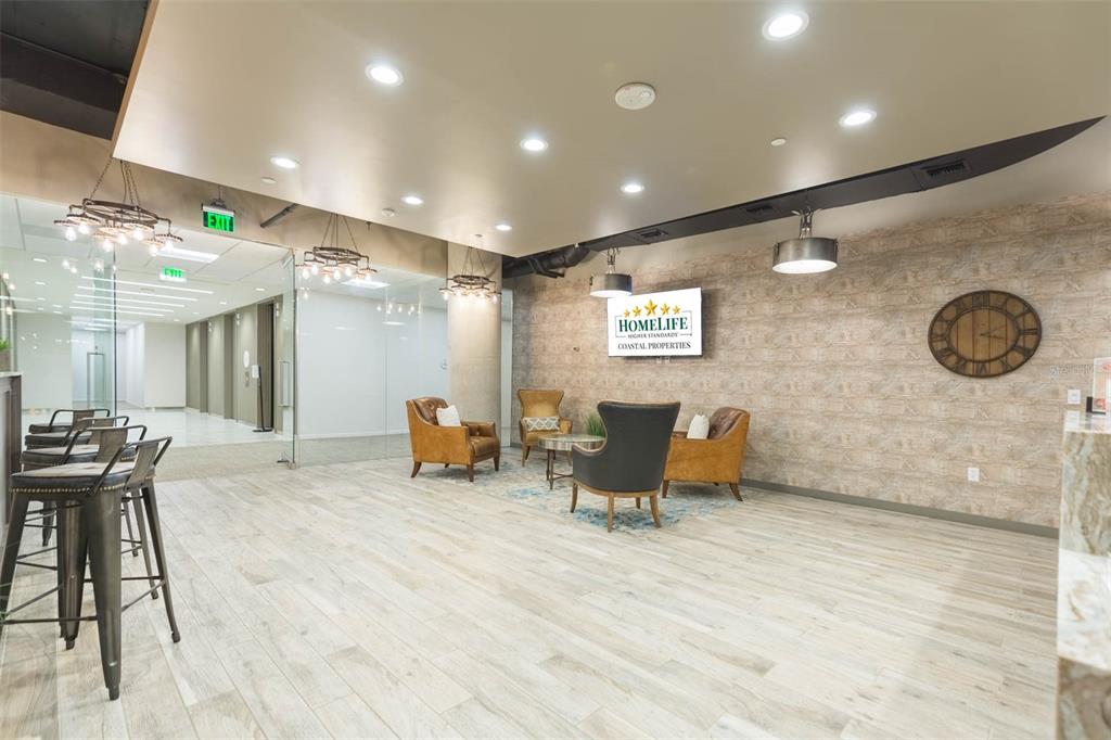 A modern office lobby features wood-look tile flooring, a seating area, and a company logo sign — 400 N ASHLEY DRIVE UNIT 2617, TAMPA, FL