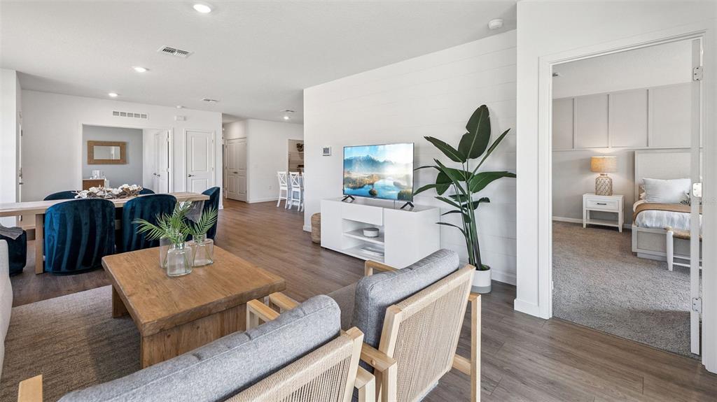 A living room with a television, two armchairs, and a view into a bedroom — 2516 KINSALE LANE, ORMOND BEACH, FL