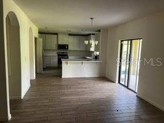An open-concept kitchen features light-colored cabinetry, a breakfast bar, and wood-look tile flooring — 4257 BROOMSEDGE CIRCLE, MELBOURNE, FL