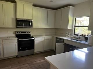 A kitchen features white cabinets, stainless steel appliances, and a light-colored countertop — 4257 BROOMSEDGE CIRCLE, MELBOURNE, FL