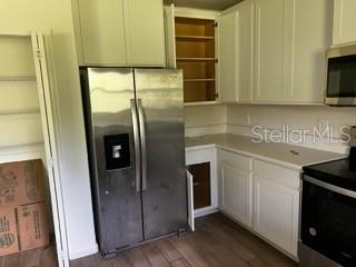 A kitchen features white cabinets, stainless steel appliances, and wood-look flooring — 4257 BROOMSEDGE CIRCLE, MELBOURNE, FL