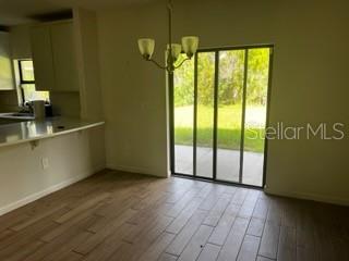 A dining area with wood-look tile floors, a chandelier, and sliding glass doors to the backyard — 4257 BROOMSEDGE CIRCLE, MELBOURNE, FL