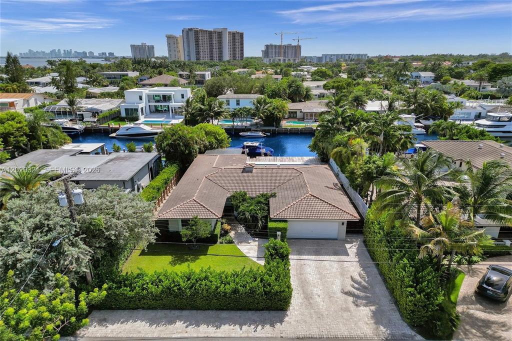 An aerial view shows a single-story house with a tiled roof, driveway, and backyard canal — 1912 NE 119TH ROAD, NORTH MIAMI, FL