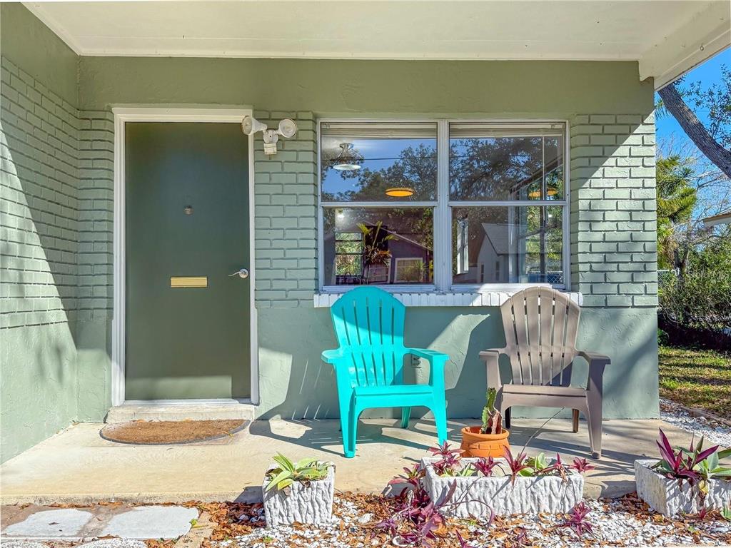 A front porch with a green door, two plastic chairs, and three concrete planters — 364 3RD STREET NW, LARGO, FL