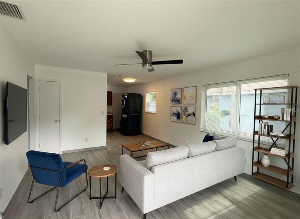 An empty room with gray wood-look tile flooring, a ceiling fan, and a stacked washer-dryer — 364 3RD STREET NW, LARGO, FL