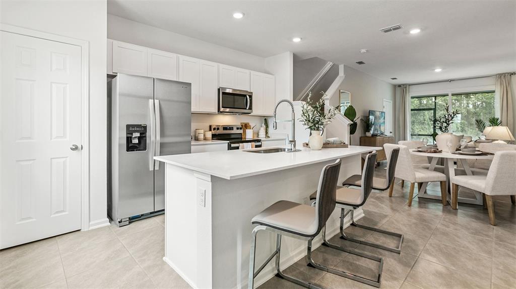 A modern kitchen features white cabinets, stainless steel appliances, a quartz island, and tile flooring — 279 AYAMONTE ROAD, ST AUGUSTINE, FL