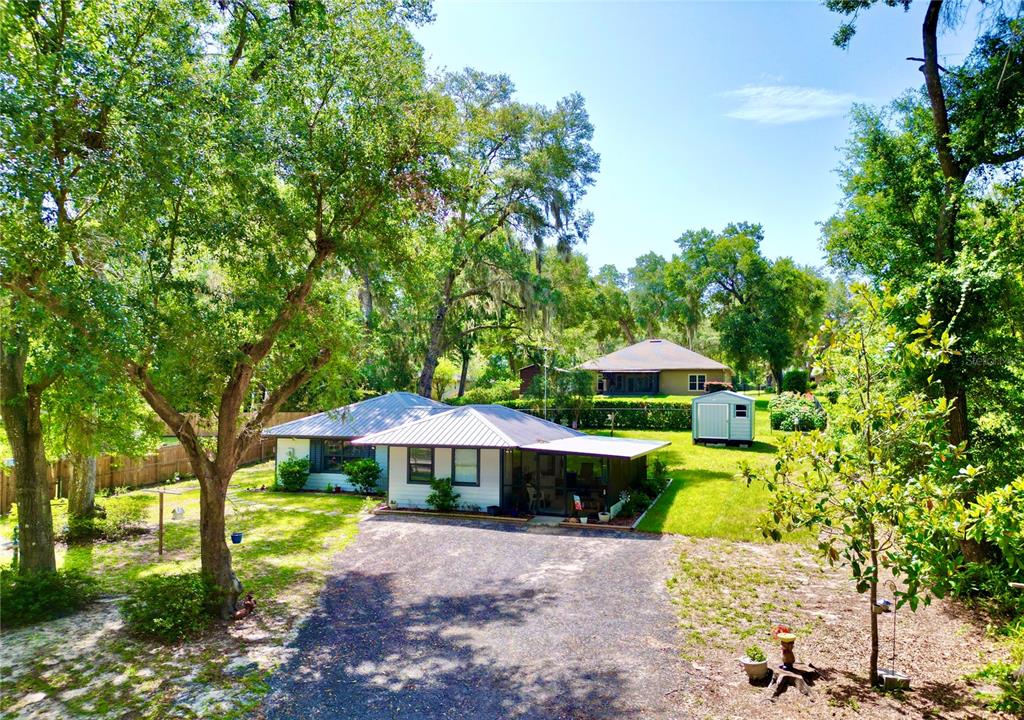 A single-story house with a metal roof, a gravel driveway, and a detached storage shed — 468 28TH WAY, MELROSE, FL