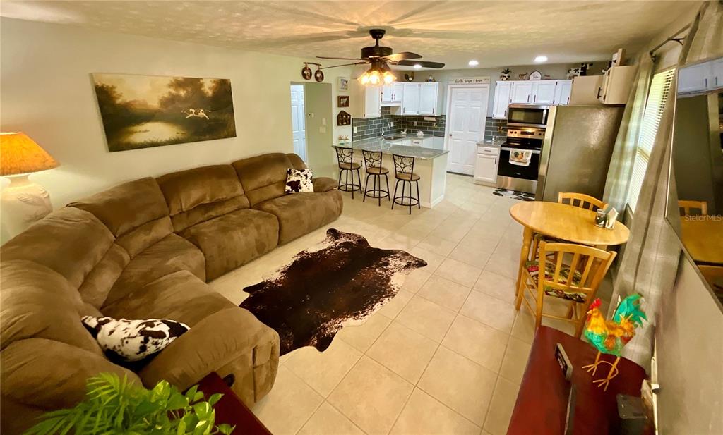 An open-concept living room and kitchen featuring a large brown sectional and tile flooring — 468 28TH WAY, MELROSE, FL