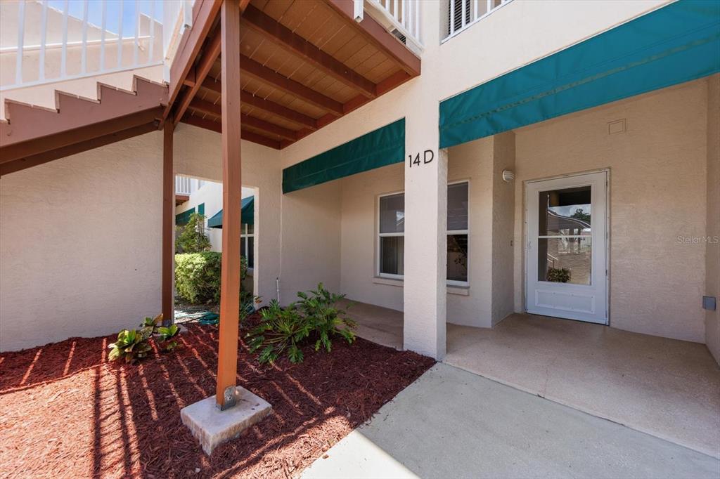 A concrete walkway leads between two beige garage buildings with white doors and gutters — 6330 99TH WAY N UNIT 14D, SEMINOLE, FL