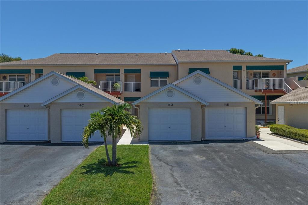 A two-story apartment building exterior features a concrete walkway leading to a ground-floor entrance — 6330 99TH WAY N UNIT 14D, SEMINOLE, FL