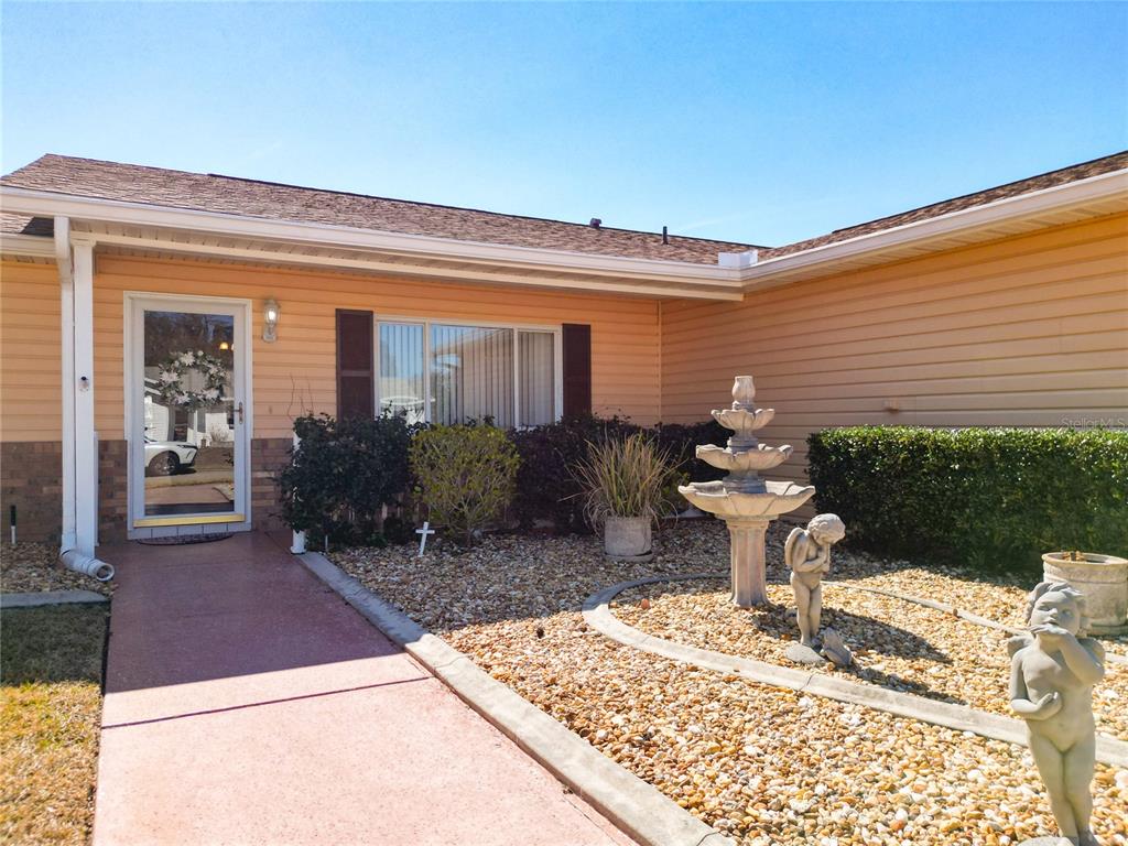 A single-story house with light yellow siding, a brick base, and a large front yard — 9826 SE 178TH LANE, SUMMERFIELD, FL