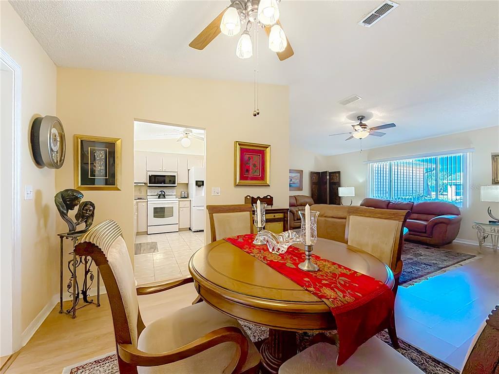 A living room with a brown sofa, glass side table, and an open front door — 9826 SE 178TH LANE, SUMMERFIELD, FL