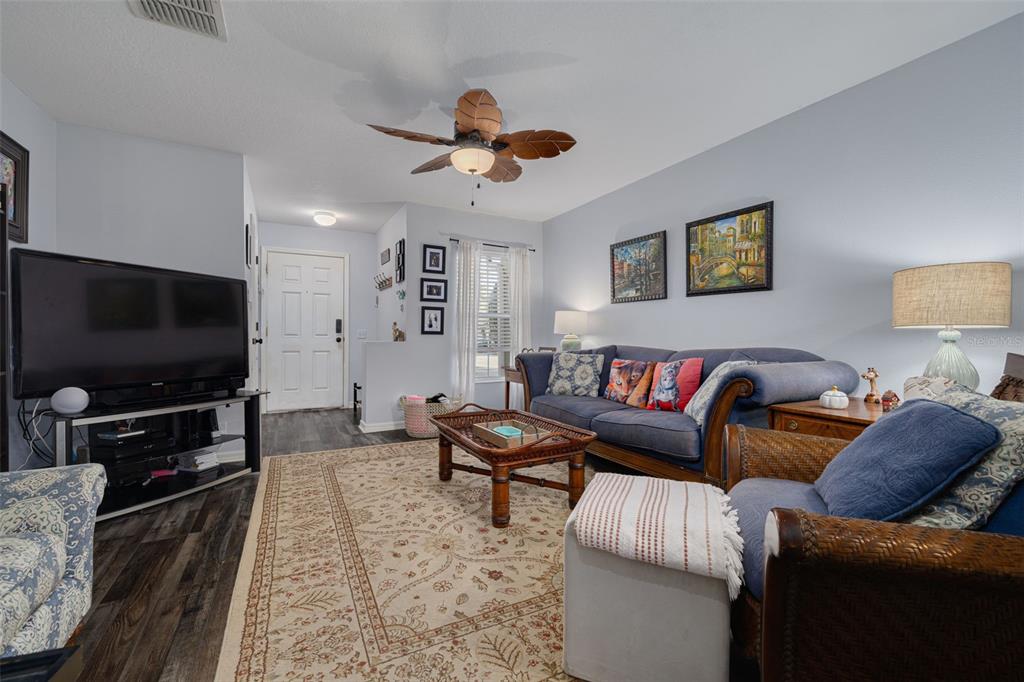 A living room features a blue sofa, a patterned area rug, and a ceiling fan — 2096 SUN DOWN DRIVE, CLEARWATER, FL
