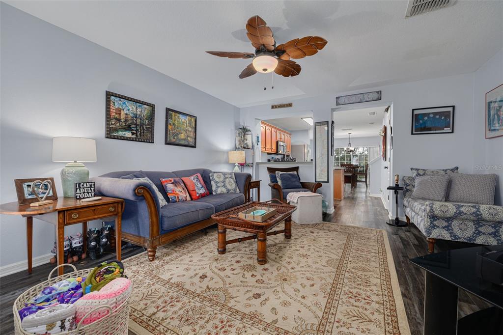 A living room features a blue sofa, a patterned area rug, and a ceiling fan — 2096 SUN DOWN DRIVE, CLEARWATER, FL