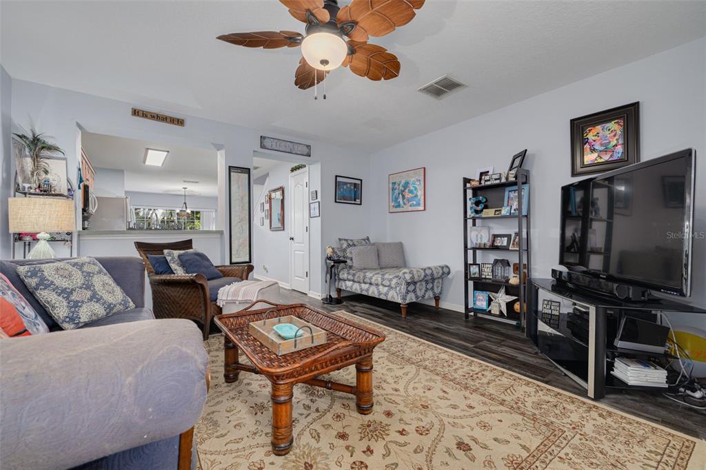 A living room features a ceiling fan, a patterned area rug, and a television console — 2096 SUN DOWN DRIVE, CLEARWATER, FL