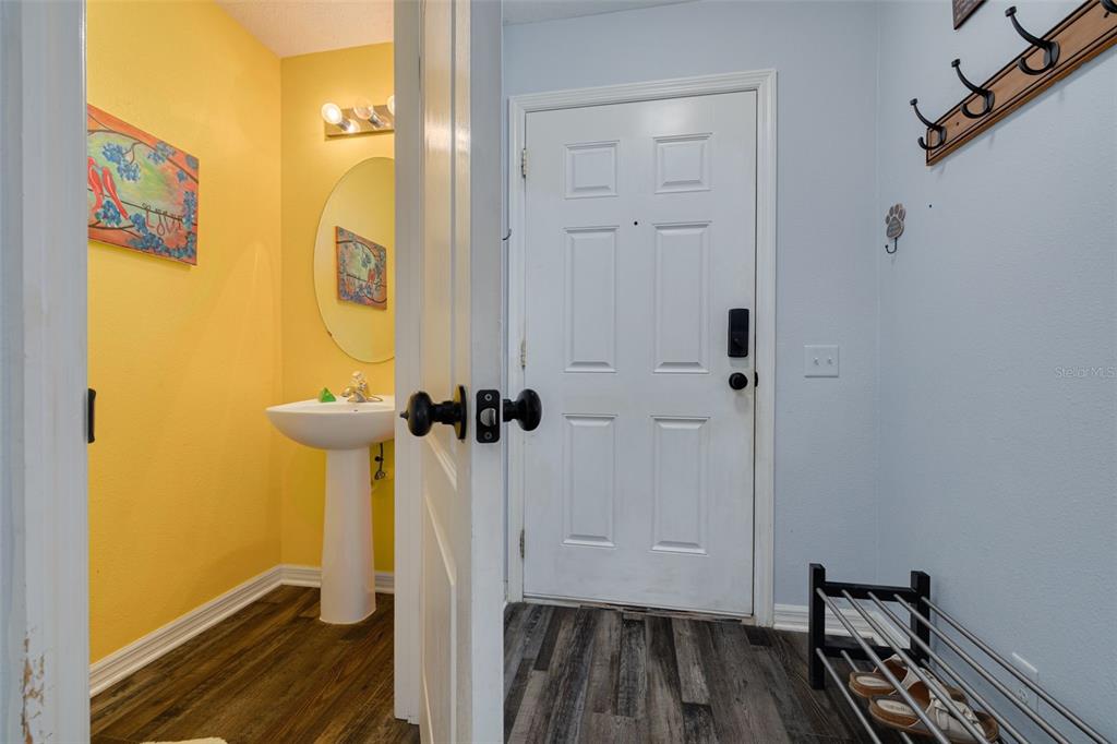 A view of a yellow powder room next to an entryway with a white door — 2096 SUN DOWN DRIVE, CLEARWATER, FL