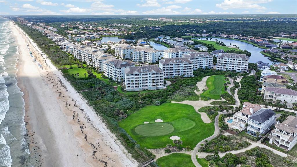 An aerial view shows a golf course fairway nestled between residential buildings and the ocean — 300 CINNAMON BEACH WAY UNIT 221, PALM COAST, FL