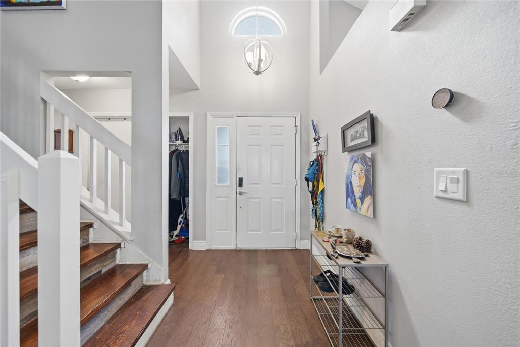 An entryway features a staircase with wood treads, a white front door, and wood flooring — 1621 SPINNING WHEEL DRIVE, LUTZ, FL